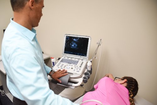 Close up of a doctor performing ultrasound on a patient while looking at the ultrasound machines screen