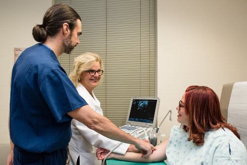 A female doctor and male nurse using a Vascular Access Doppler on a patient